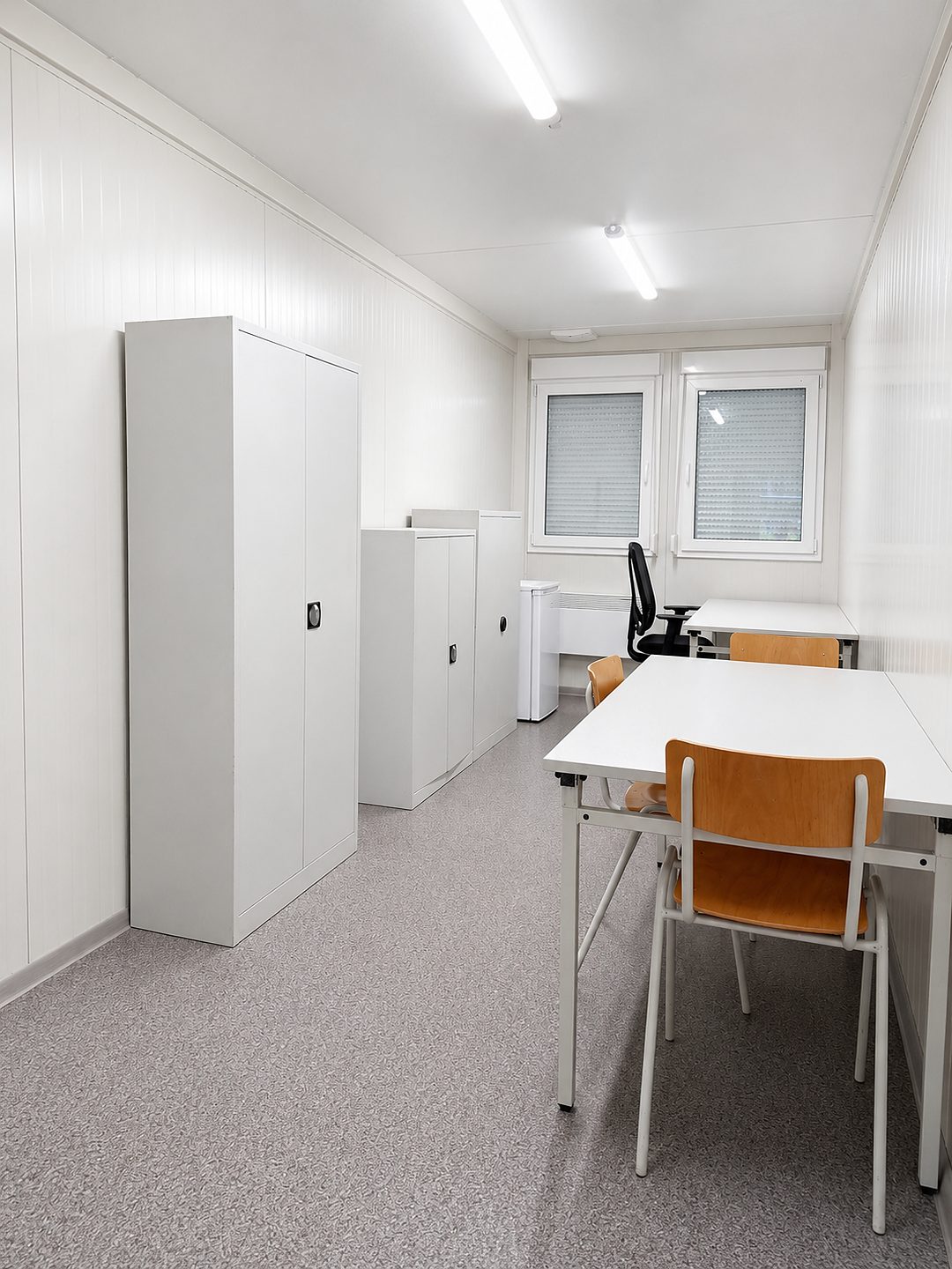 Aufenthaltsbereich mit weißem Schrank, Tisch und orangefarbenen Stühlen