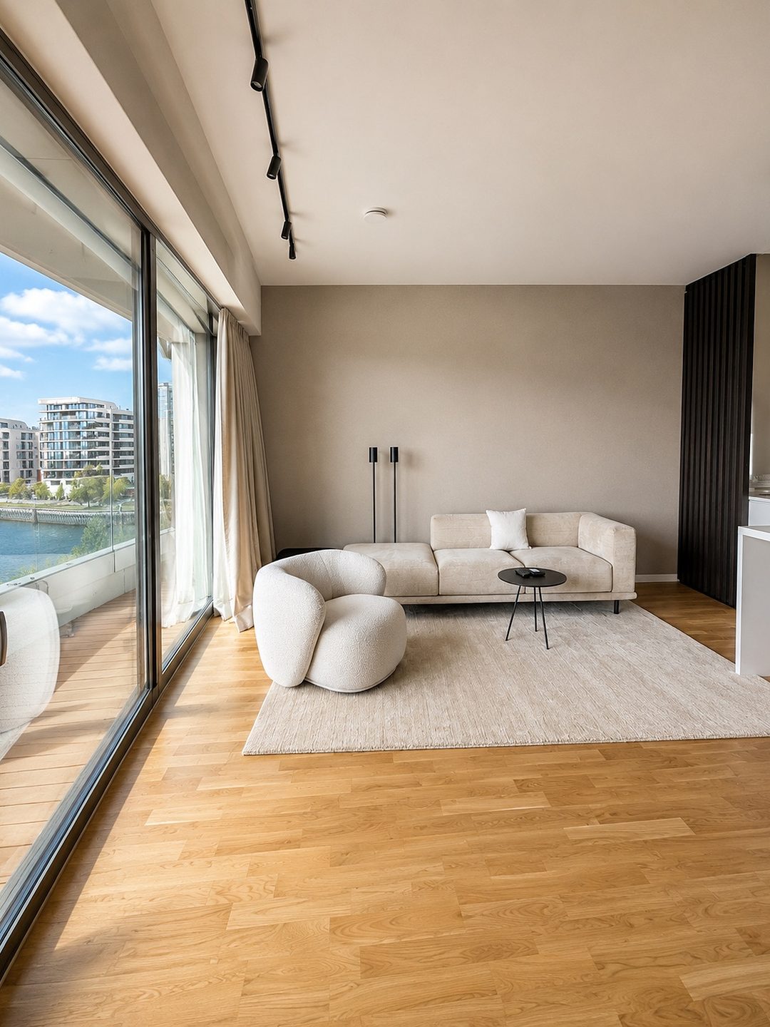 Gepflegter Wohnbereich mit hellem Sofa und Blick auf das Wasser in einer Musterwohnung in der HafenCity